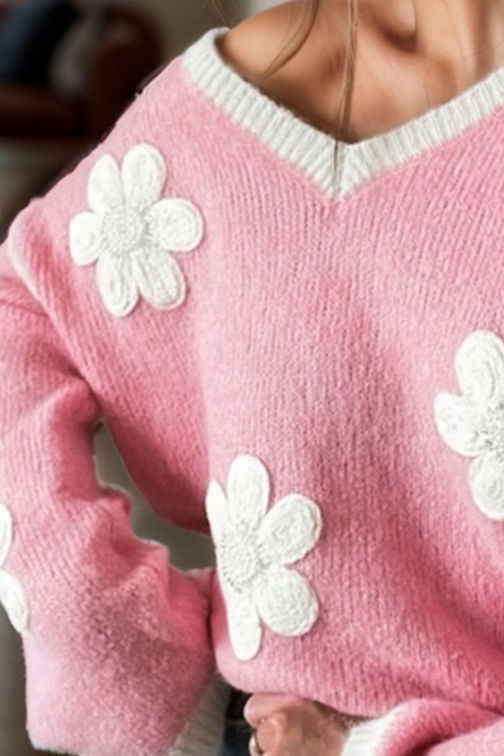 Pink knit sweater with white daisy appliqués and a v-neck.