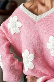 Pink knit sweater with white daisy appliqués and a v-neck.