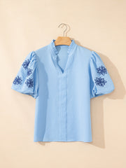 Light blue textured blouse with embroidered puff sleeves and ruffled neckline