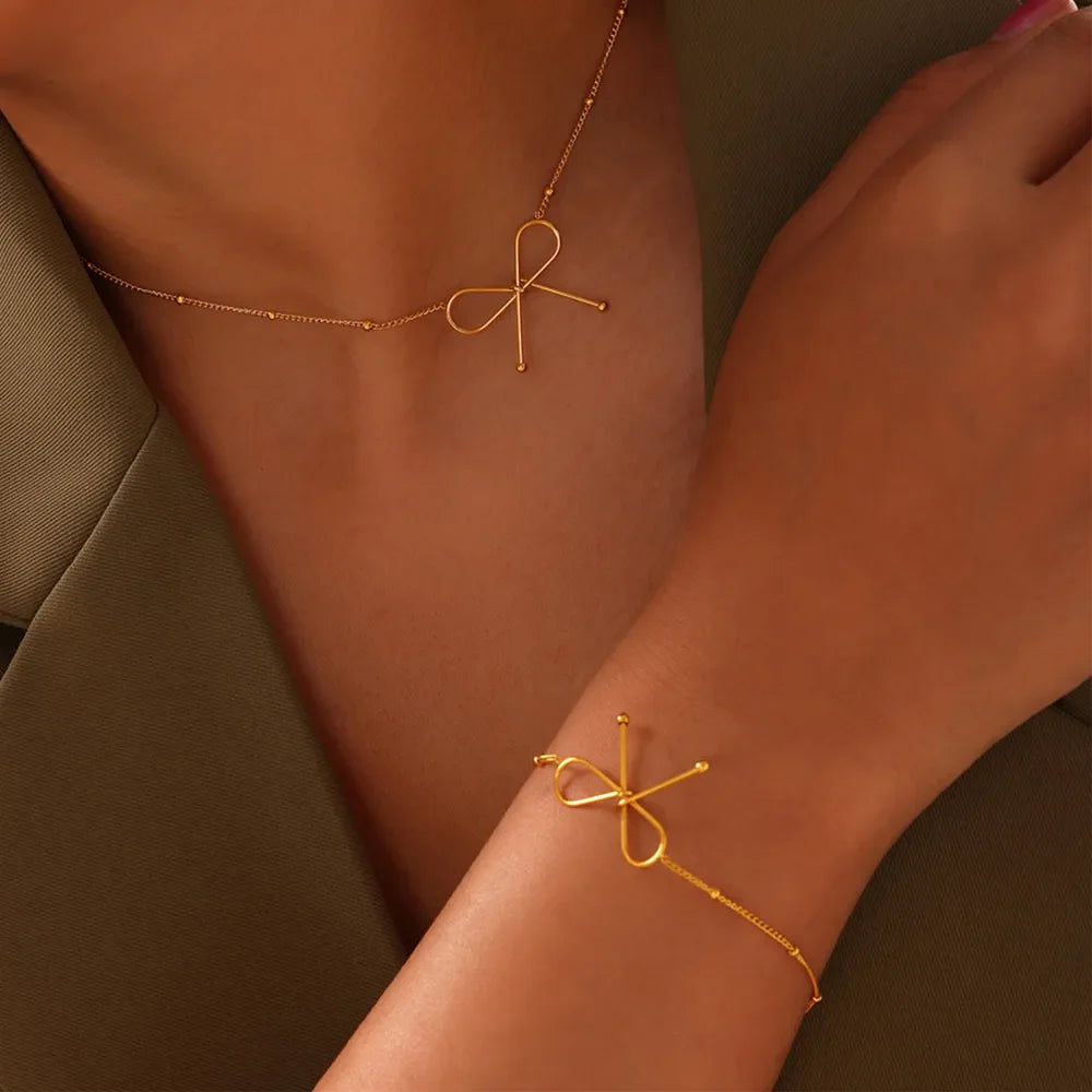 Gold delicate bow silhouette bracelet with beaded chain detail.