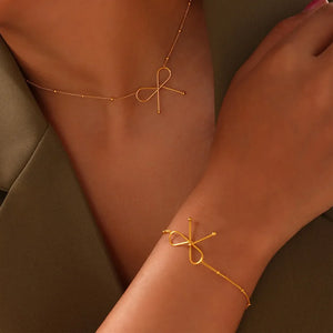 Gold delicate bow silhouette bracelet with beaded chain detail.