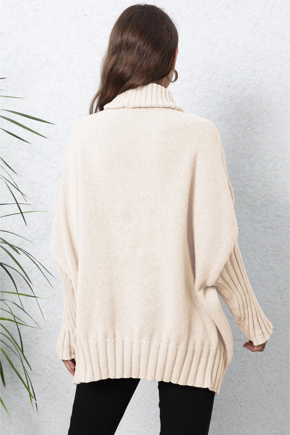 Beige knit turtleneck sweater with batwing sleeves and ribbed details.