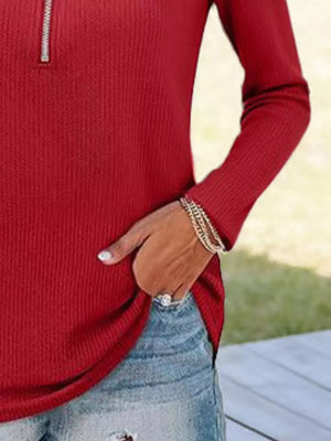 Burgundy ribbed knit half-zip sweater with long sleeves, styled with jeans.