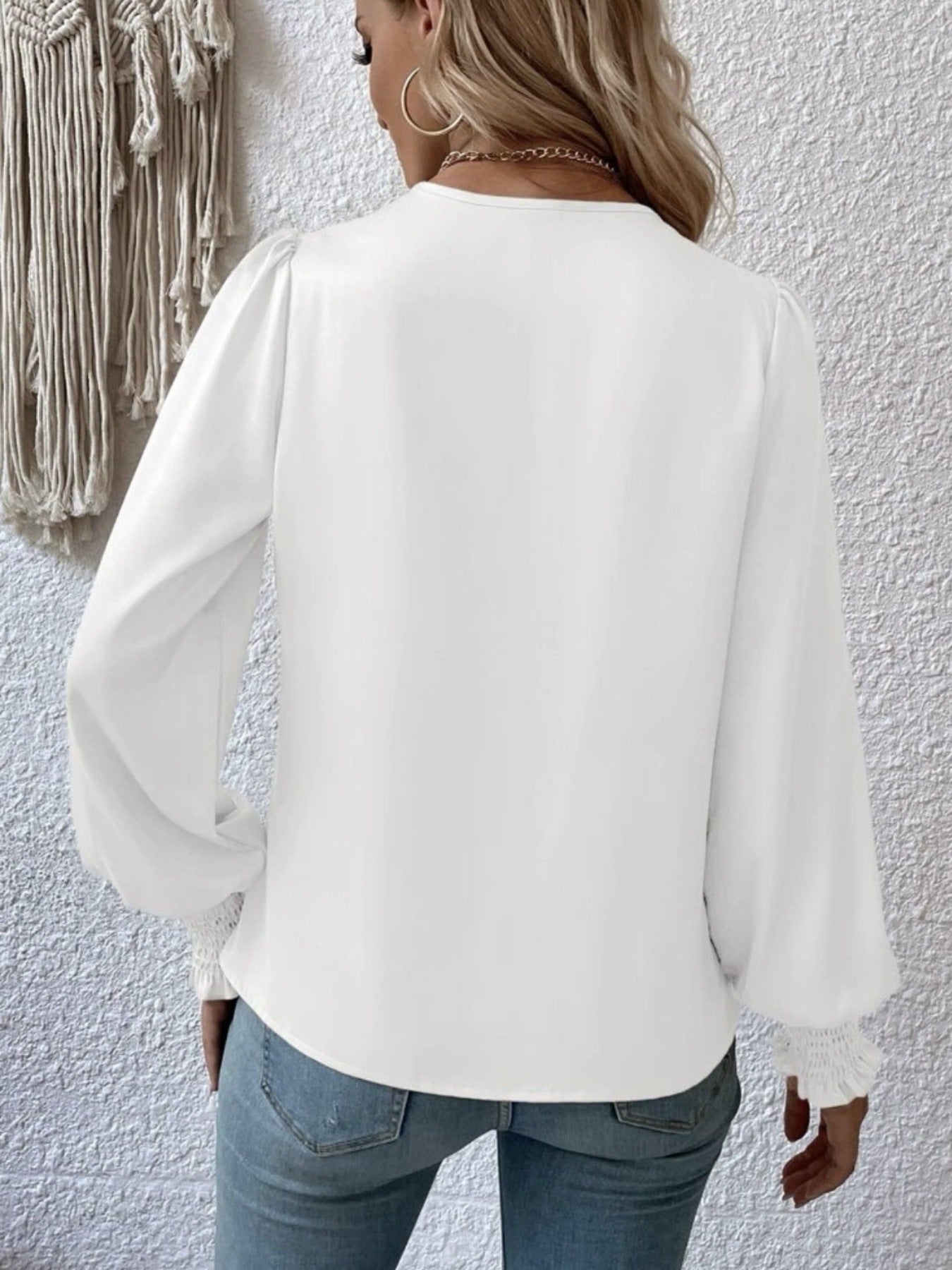 White ruched surplice blouse with long puff sleeves and smocked cuffs.