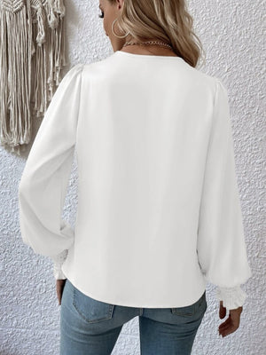 White ruched surplice blouse with long puff sleeves and smocked cuffs.
