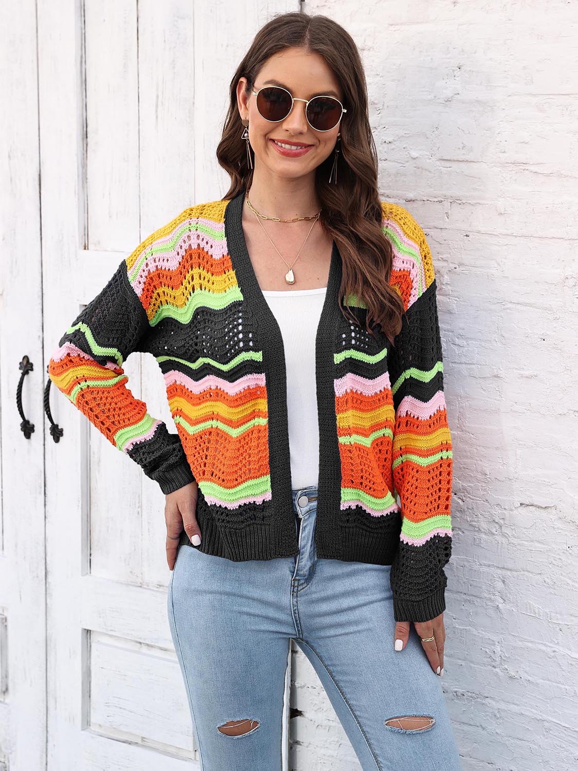 Rainbow wave crochet cardigan with black trim, open front, long sleeves, and colorful chevron pattern.