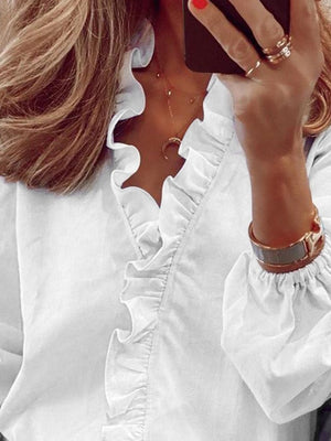 White blouse with cascading ruffle front and balloon sleeves.