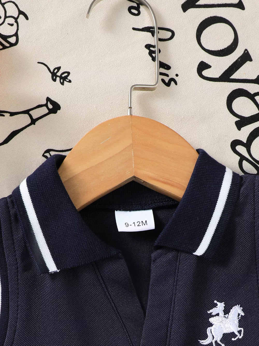Navy sleeveless polo dress with white equestrian embroidery and striped collar.