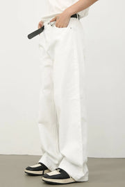 Sculpted wide leg denim trousers in ivory, styled with a belt and sneakers.