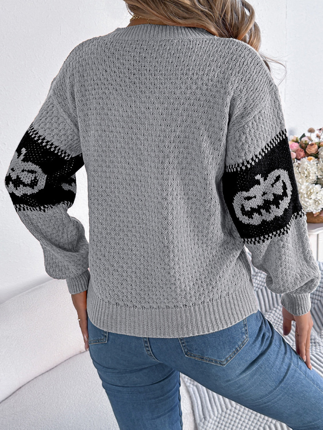 Gray knit sweater with jack-o'-lantern intarsia on sleeves.