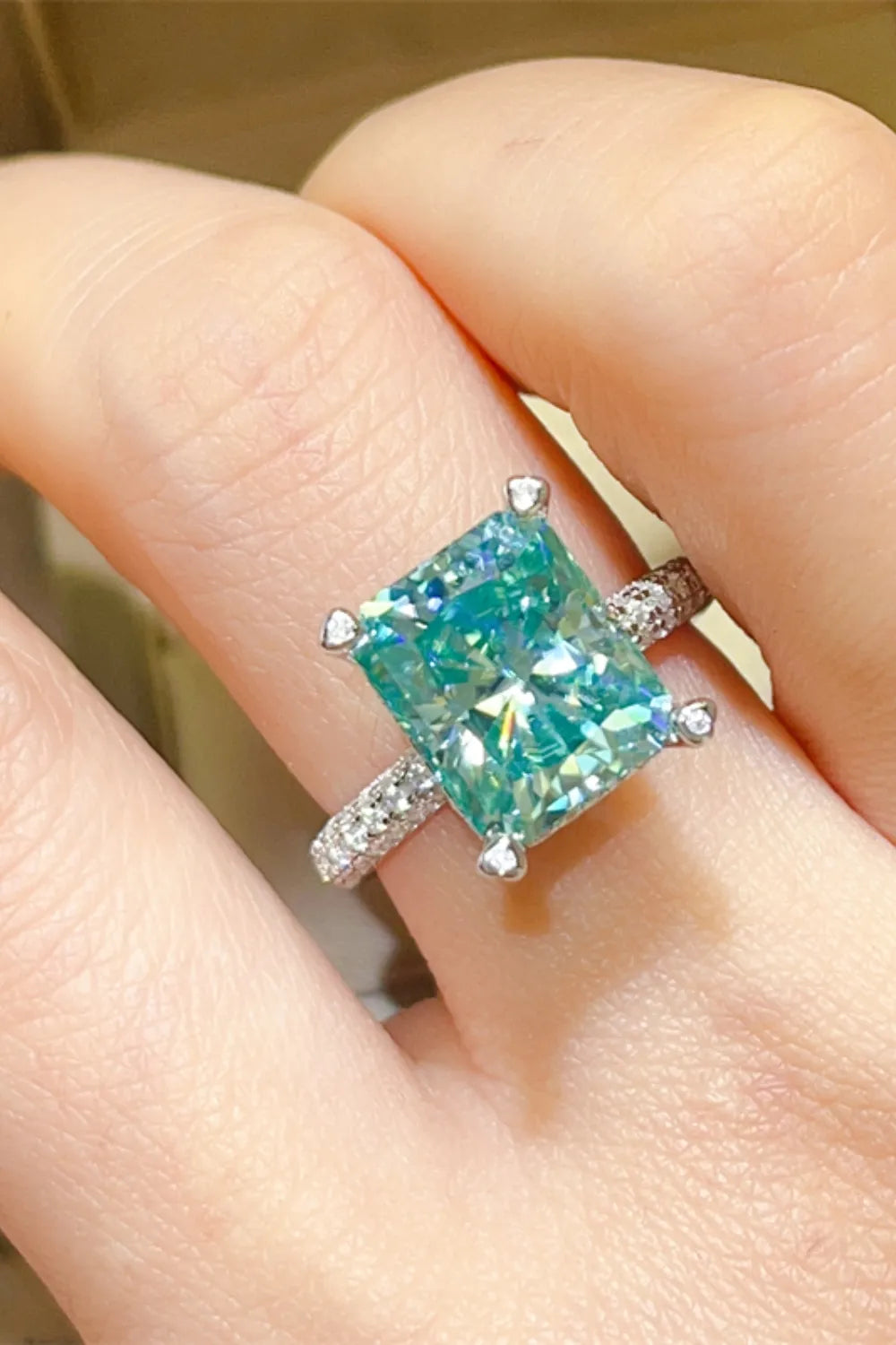Radiant emerald cut teal diamond ring with pave band.