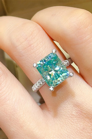Radiant emerald cut teal diamond ring with pave band.