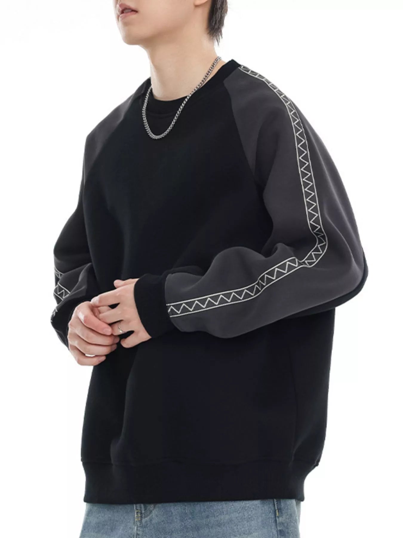 Black oversized raglan sleeve sweatshirt with gray contrast sleeves featuring white zigzag stitching detail.