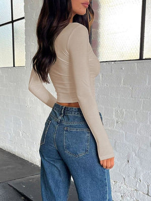 Sculpted ribbed V-neck crop top in beige with long sleeves.