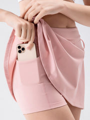 Blush pink wrap skort with side tie detail and pocket holding a phone.