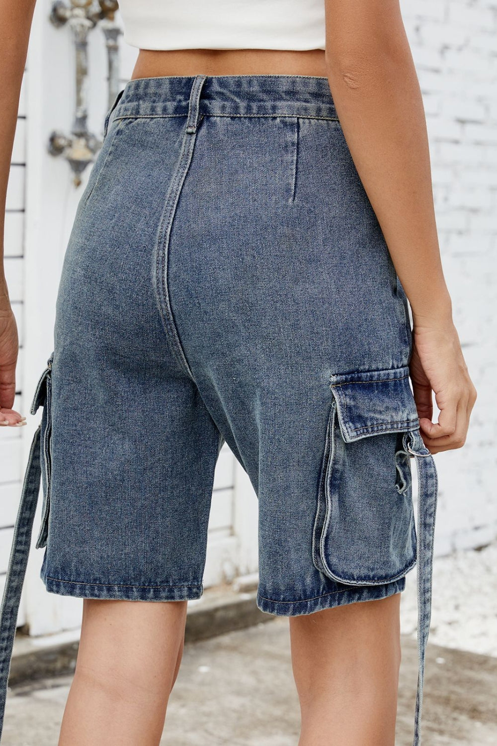 Medium blue denim cargo shorts with straps and flap pockets.