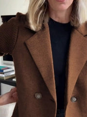 Brown double-breasted trench coat with knit sleeves and notched lapels.