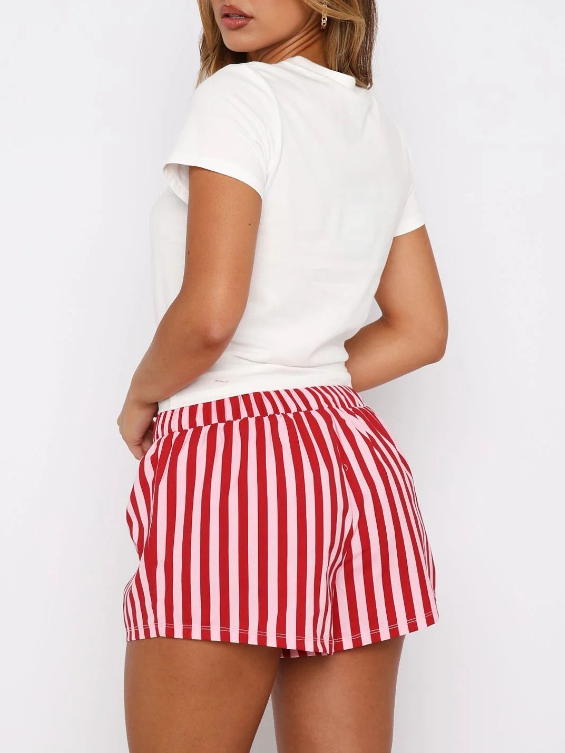 White graphic tee and red and pink striped lounge shorts with a drawstring waist.