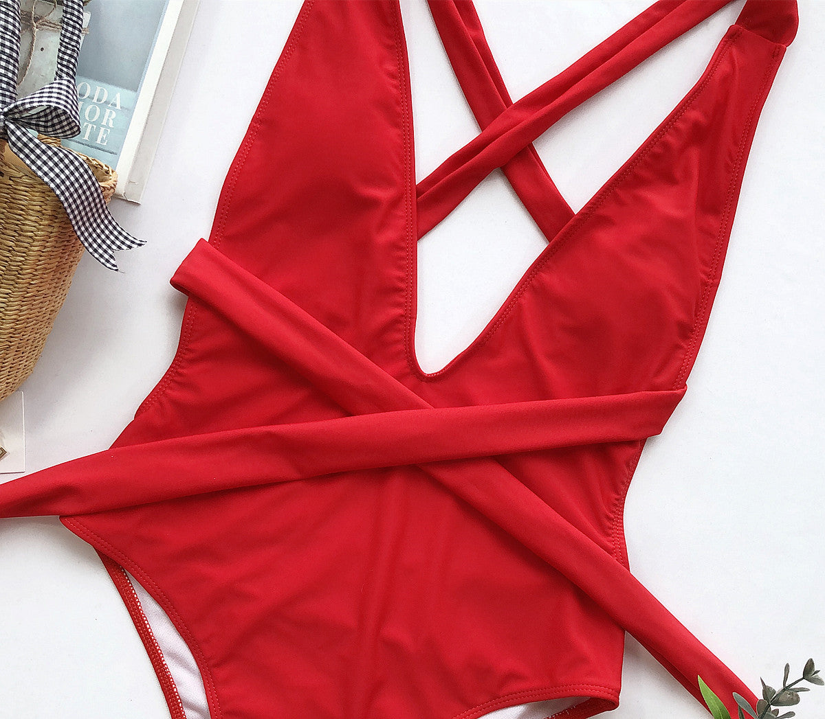 Red wrap-around halterneck plunge swimsuit with crisscross straps and a tie waist.