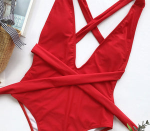 Red wrap-around halterneck plunge swimsuit with crisscross straps and a tie waist.