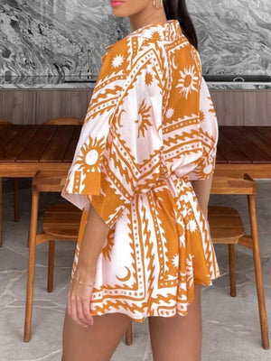 Wrap romper in gold with celestial print, short sleeves, and adjustable fit.
