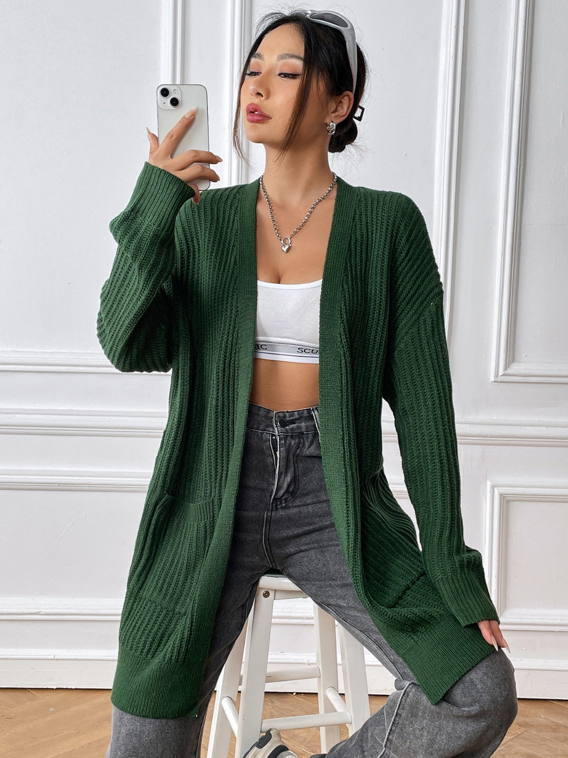 Ribbed knit pocket cardigan in Black Forest green acrylic with long sleeves and an open front.