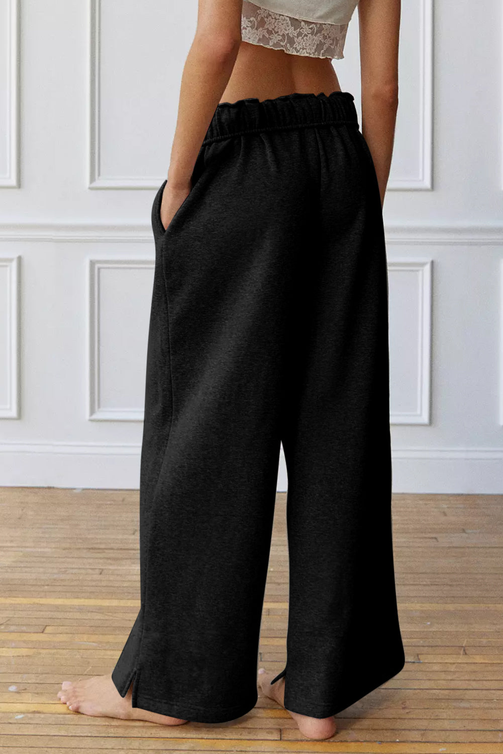 Black relaxed palazzo lounge trousers with a ruffled elastic waistband and side slits.