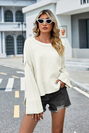 Cream acrylic knit sweater with flared sleeves and slit hem detail.
