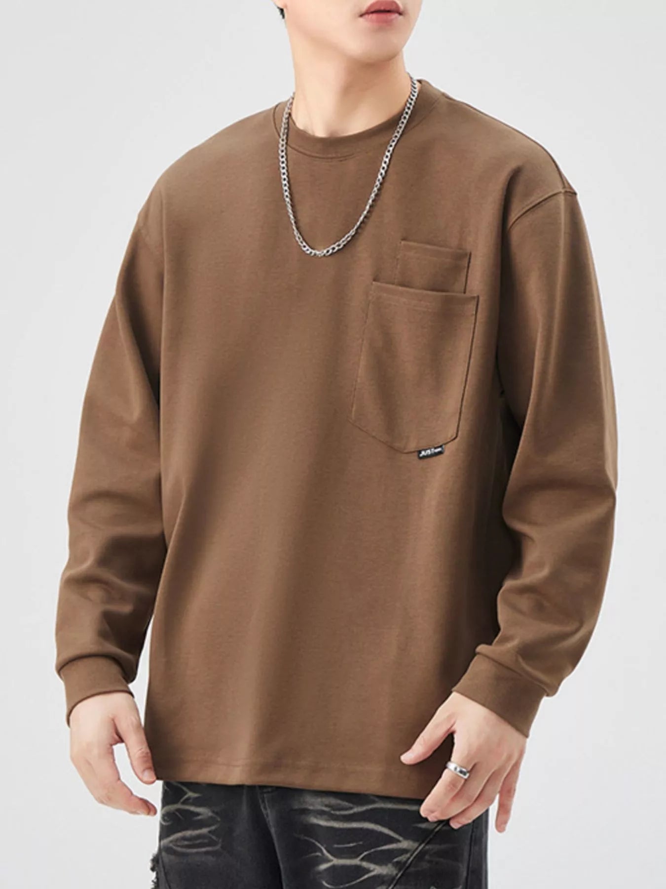 Brown long-sleeve sweatshirt with chest pocket and crew neck.