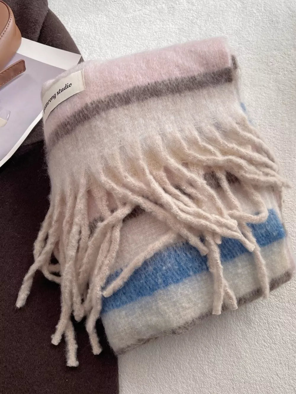 Plush multi-patterned scarf with fringe in pink, blue, and brown stripes.