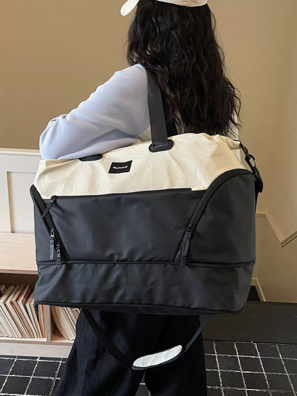 Textured two-tone large duffle bag in black and cream with adjustable strap.