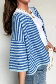Cropped blue striped knit cardigan with buttons and a v-neck, worn over a white top.