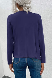 Dark blue jacket with long sleeves and a draped front, styled with jeans.