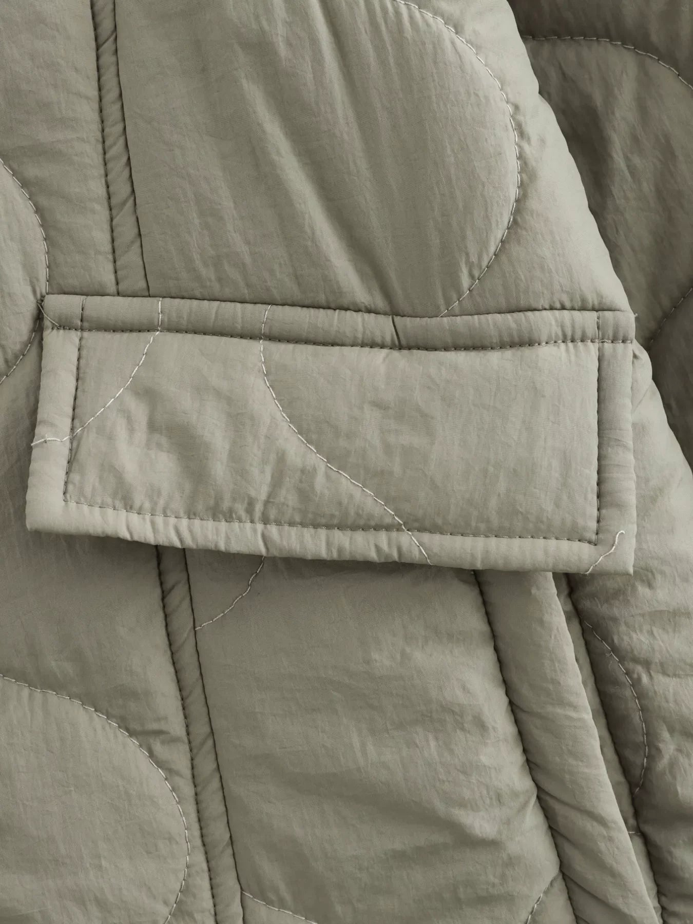 Lined quilted button-down jacket in moss green with a patch pocket and white contrast stitching.