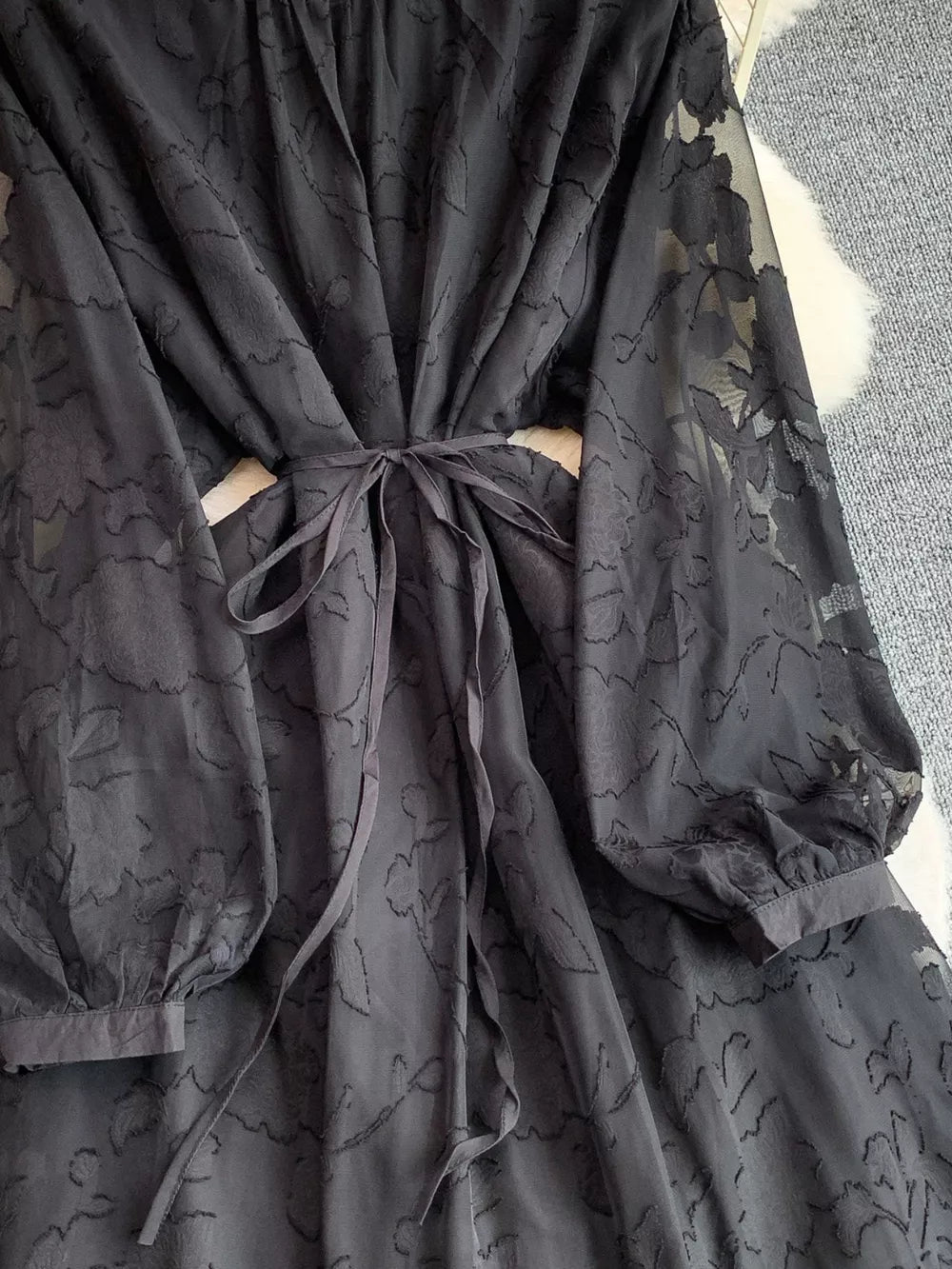 Black embroidered tie-waist dress with sheer floral sleeves.