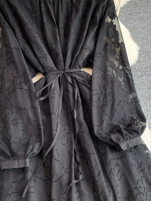 Black embroidered tie-waist dress with sheer floral sleeves.