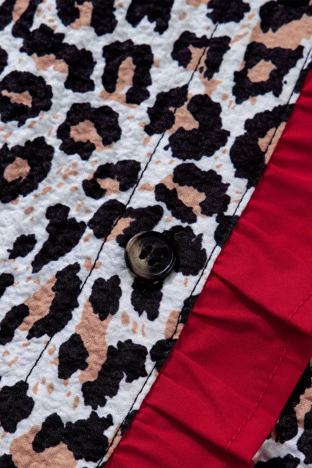 Leopard print V-neck shirt with red frill detail and button closure.