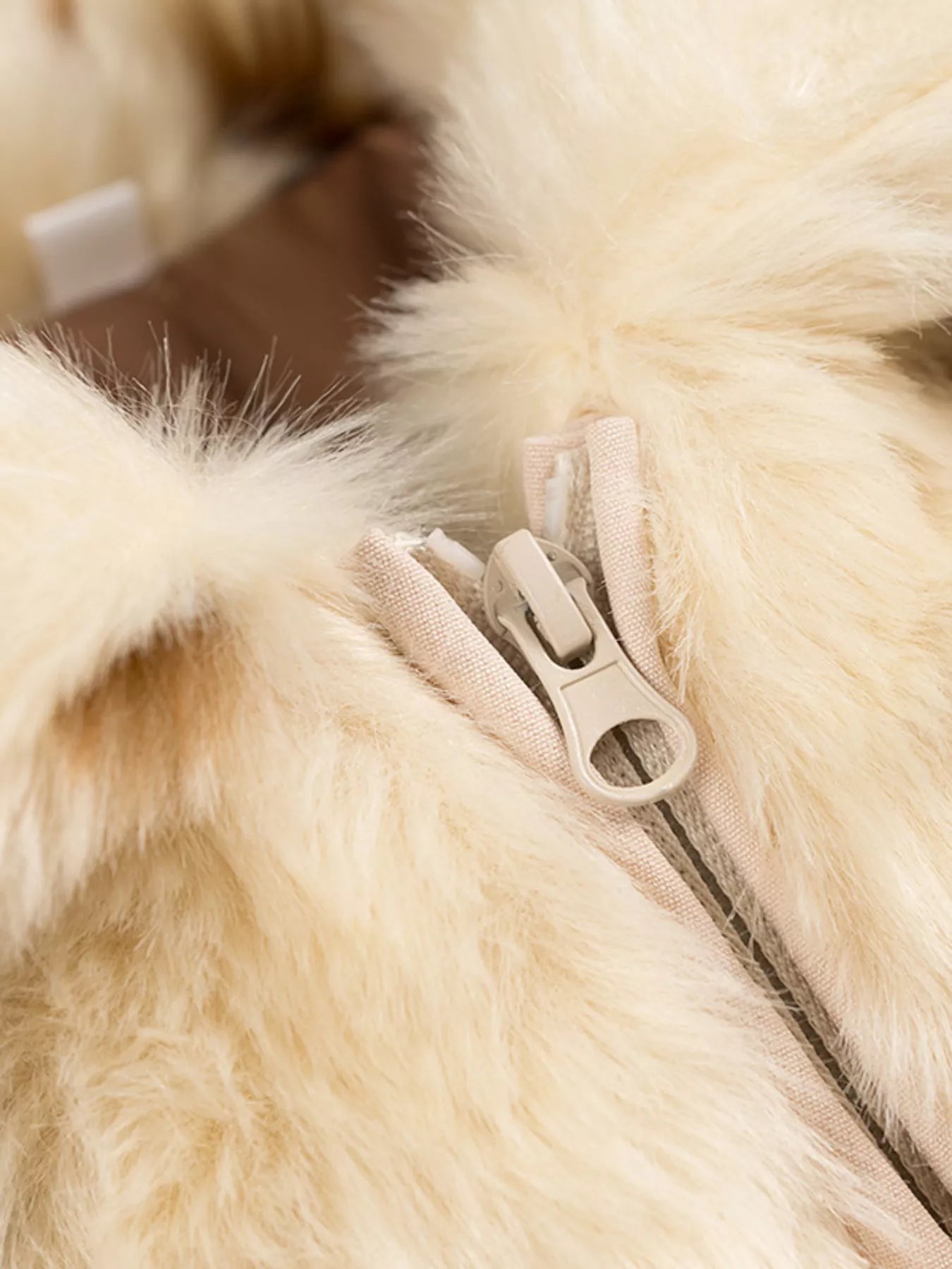 Beige faux fur cropped jacket with a zip-up closure and textured trim.