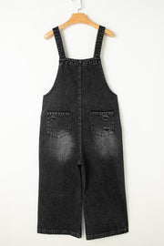 Black denim culotte overalls with distressed details and wide legs.