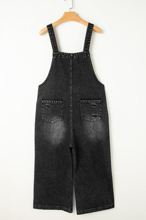 Black denim culotte overalls with distressed details and wide legs.