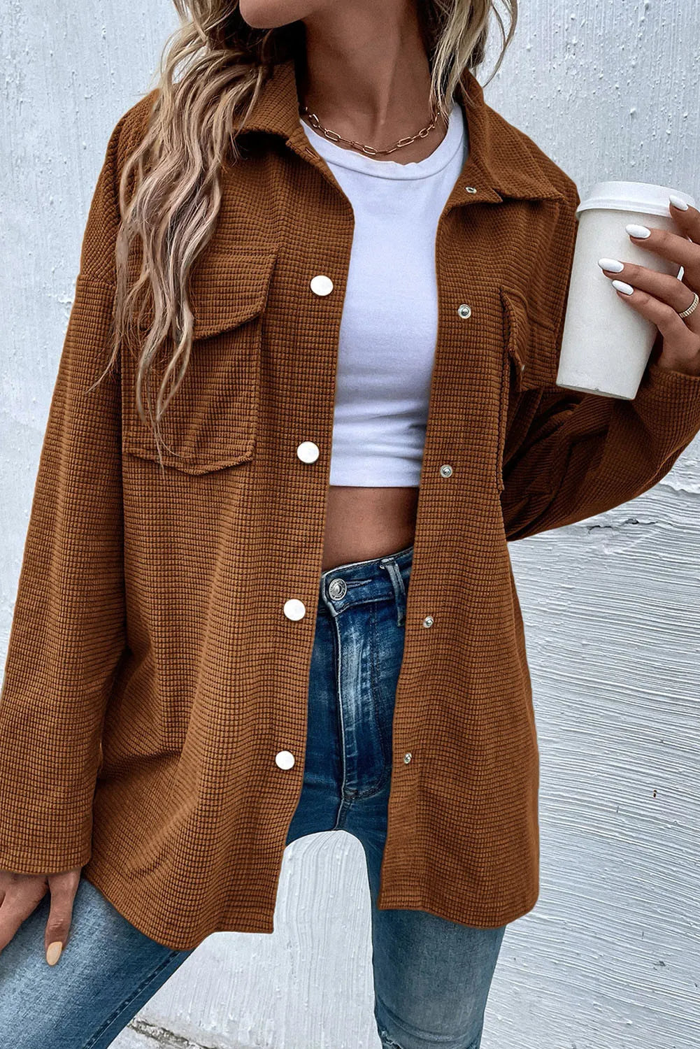 Brown waffle knit overshirt with patch pockets and white buttons, worn open over a white crop top.