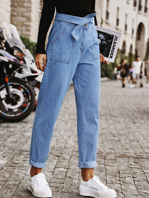 Belted high-waist light wash denim barrel trousers with cuffed hems.