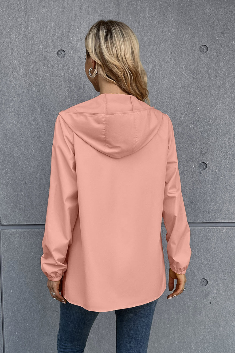 Blush pink hooded rain coat with long sleeves and elastic cuffs.