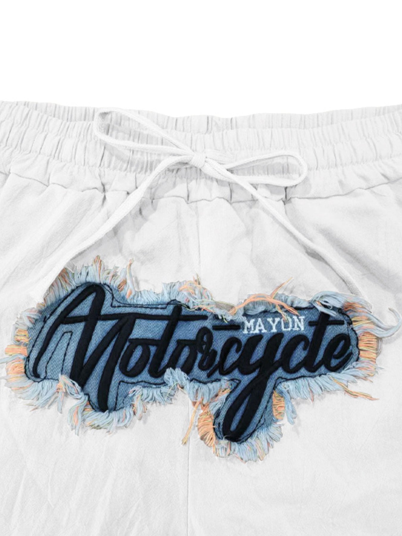 White drawstring sweatpants with a distressed denim patch featuring black embroidered "Motorcycle" text.