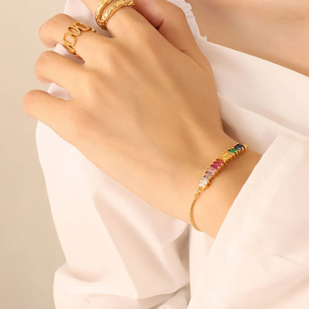 Rainbow baguette zirconia bar bracelet with adjustable clasp on a gold chain.