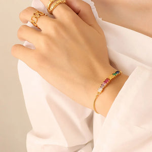 Rainbow baguette zirconia bar bracelet with adjustable clasp on a gold chain.