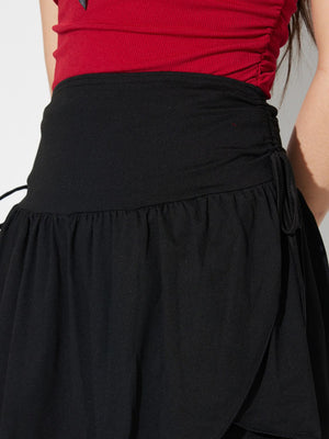 Black draped wrap mini skirt with tie detail and ruffled hem