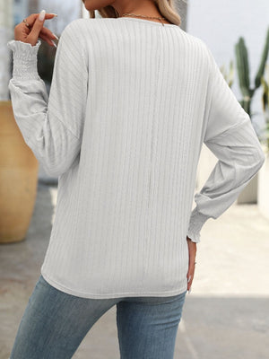 White textured sleeve blouson top with smocked cuffs and a relaxed fit.