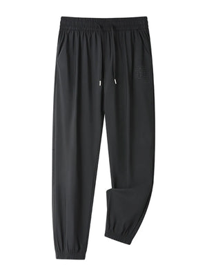 Black drawstring joggers with elastic cuffs and a subtle embossed logo detail.