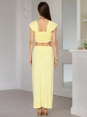 Yellow ruched crop top with cap sleeves and a square neckline, paired with a matching maxi skirt.